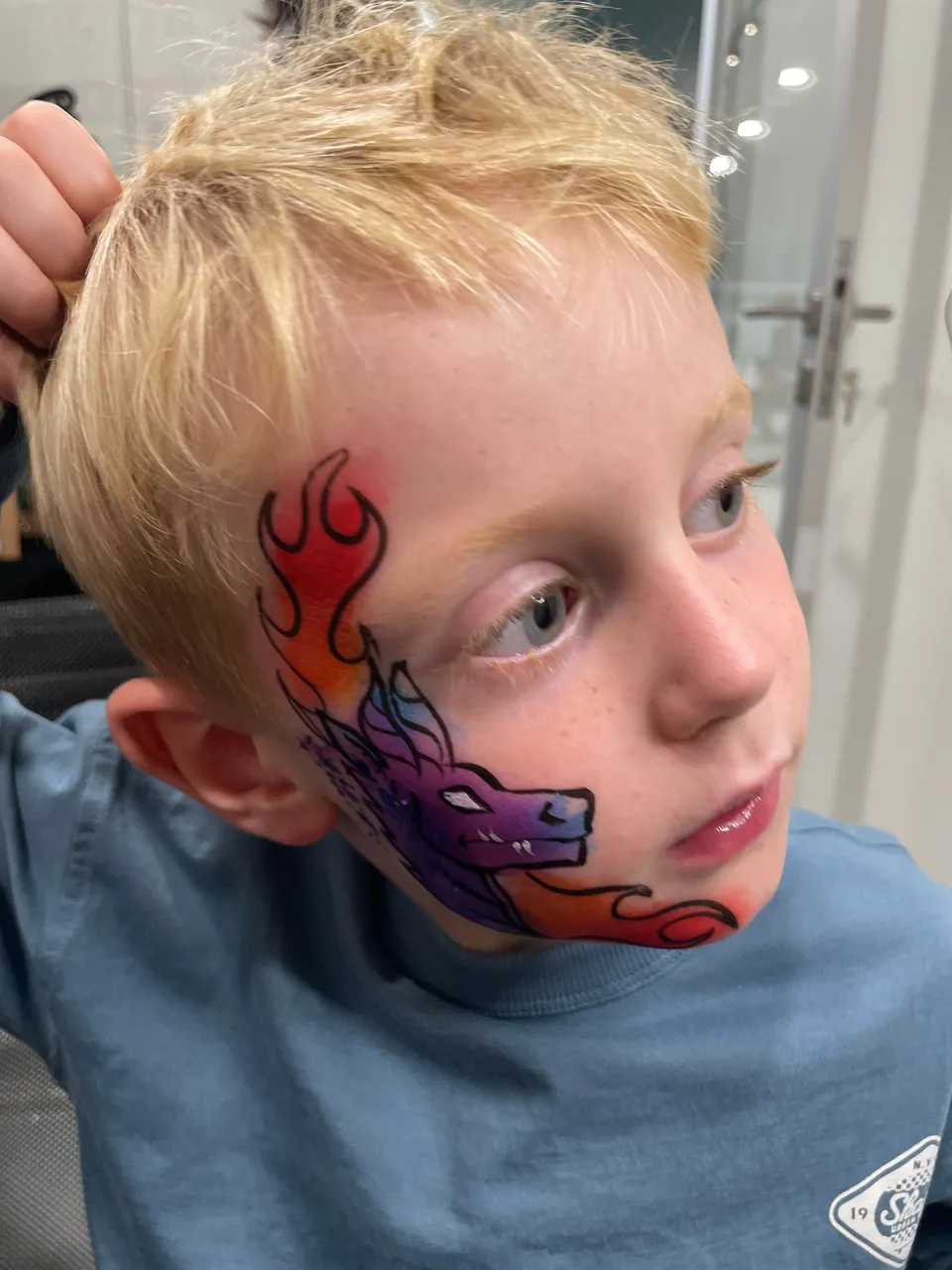 Dragon violet et flammes sur la joue d’un garçon