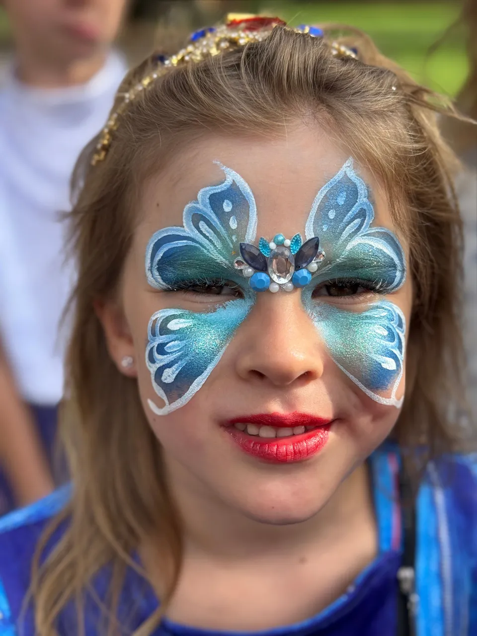 Maquillage papillon bleu et blanc sur le visage d’une fillette