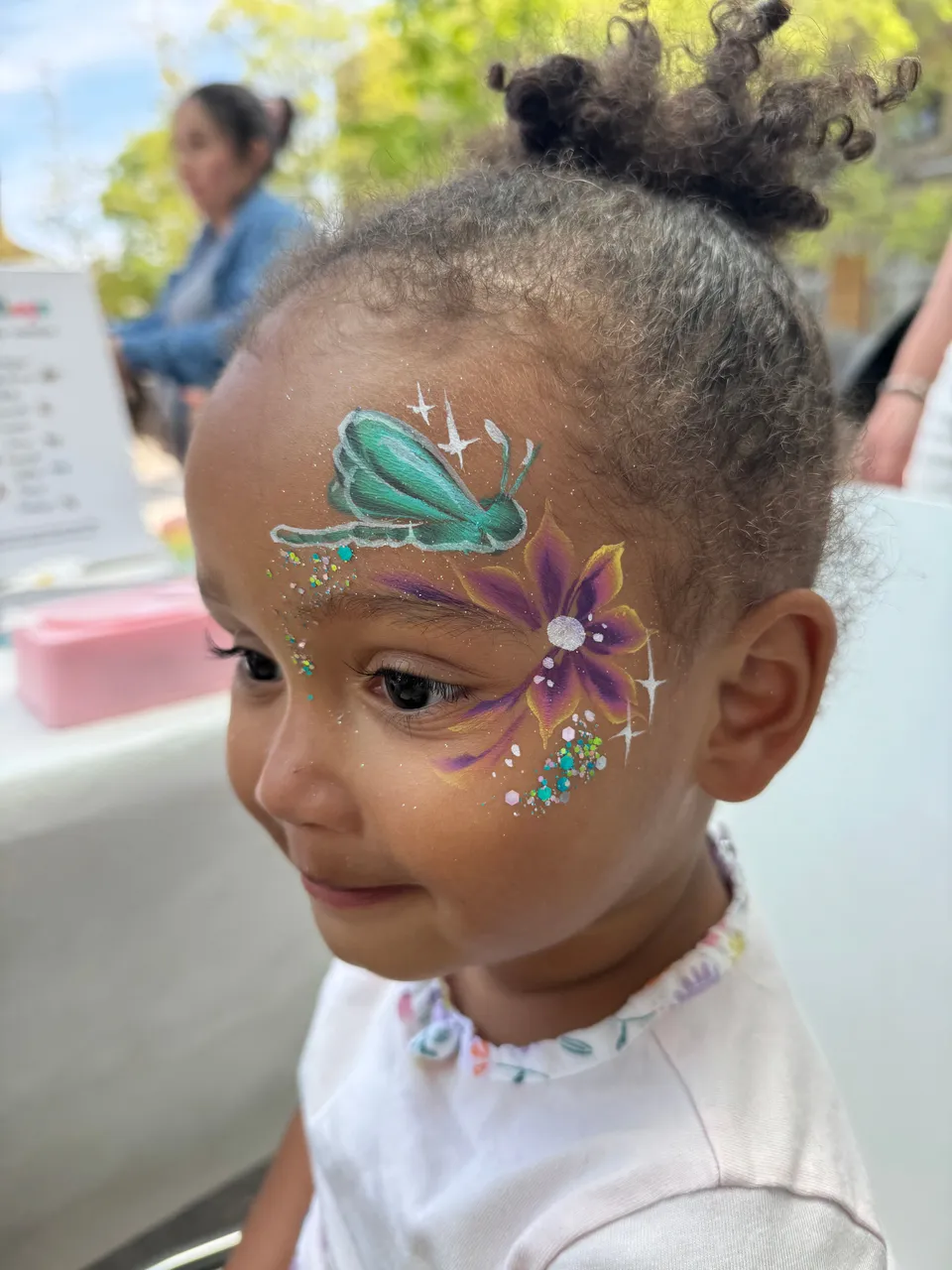 Libellule turquoise et fleur violette sur la tempe d’une petite fille